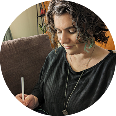 Ilana of Ilana Leah LLC, a white woman with medium length curly dark hair looking down at an iPad she is drawing on