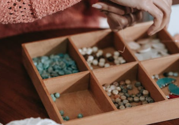 Cropped image of a woman's hands over a bead organizer; ecommerce and etsy setup and small business branding and marketing
